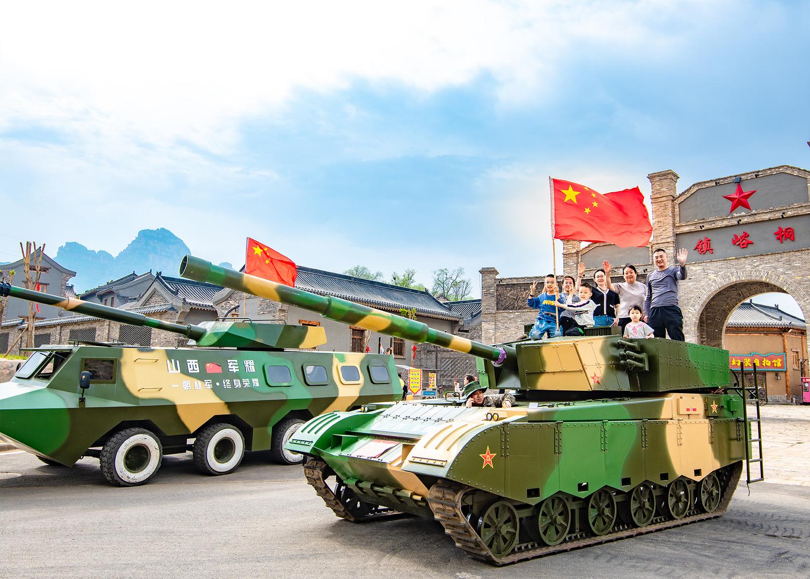 晋中市左权县1941小镇内,两辆退役坦克成为热门打卡地,众多亲子家庭在此驻足合影。