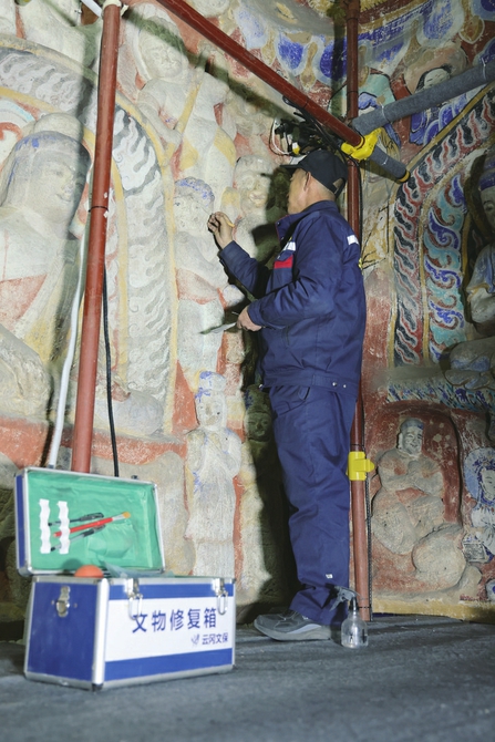 文物修复人员正在修复佛像。云冈石窟景区供图