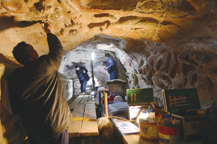 文物修复人员对石窟顶部进行修复。