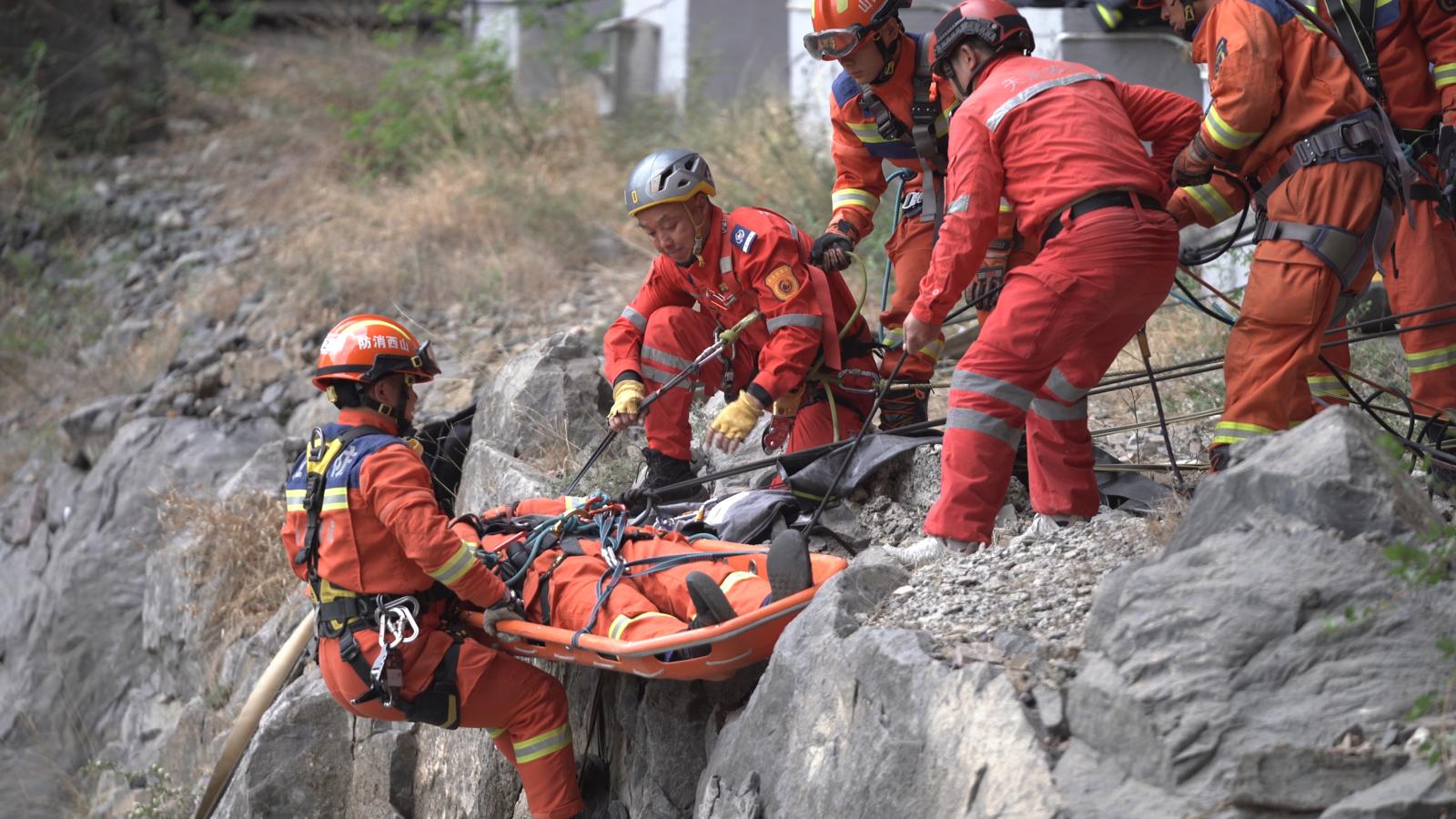 消防救援人员为“被困人员”穿戴安全吊带,固定在担架上,将“伤员”成功转运至安全区域。