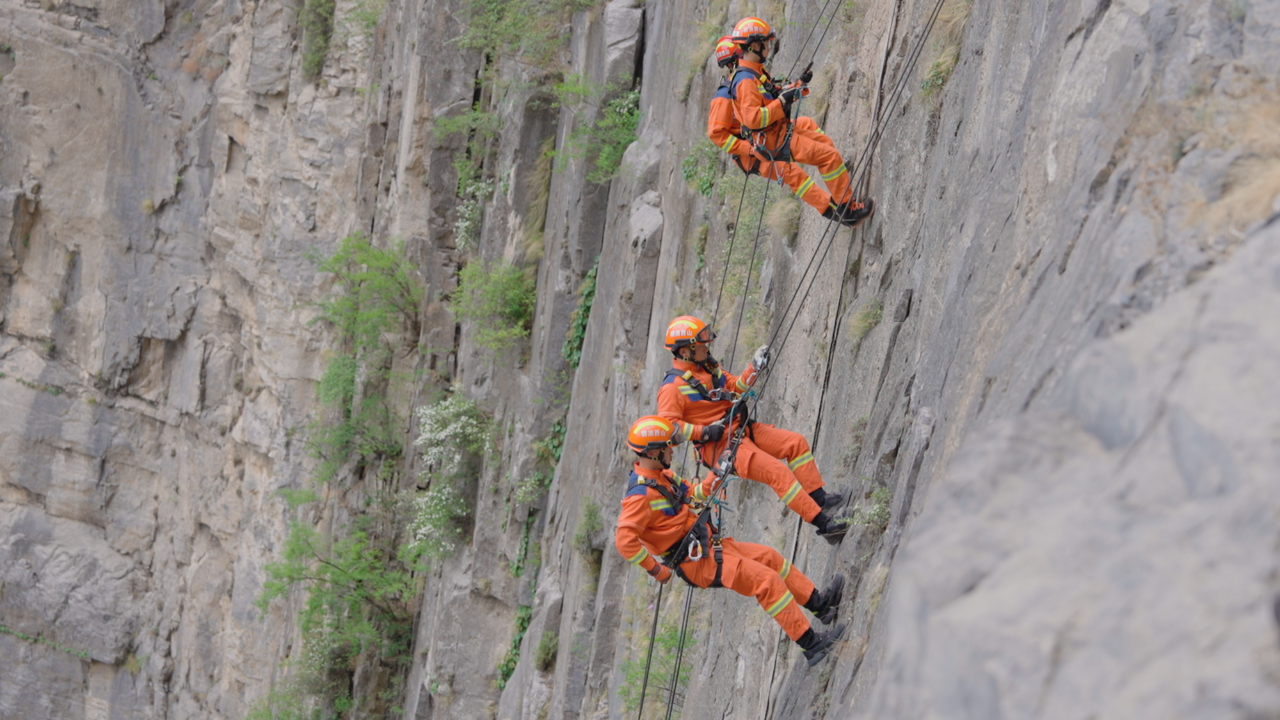 实战模拟崖壁救援时救援人员下至山底途中。