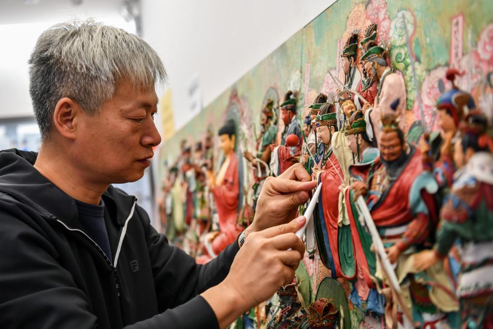 在忻州古城,面塑技艺非遗传承人卢佩宏在制作面塑(10月21日摄)。