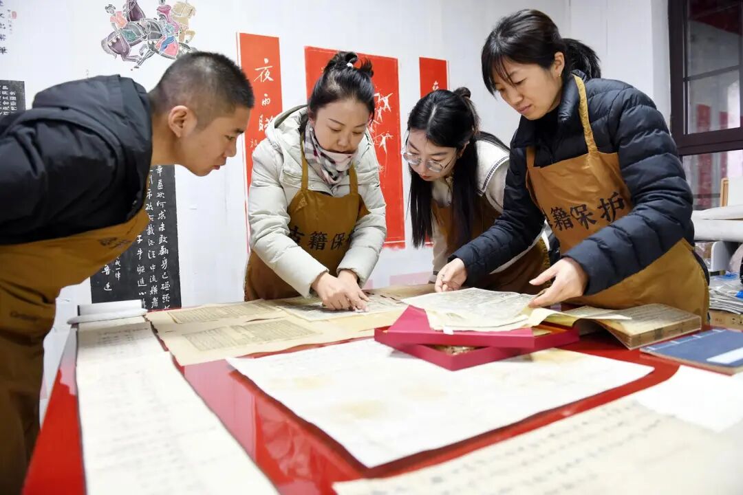 闫宇霞(左二)和同事一起修复古籍