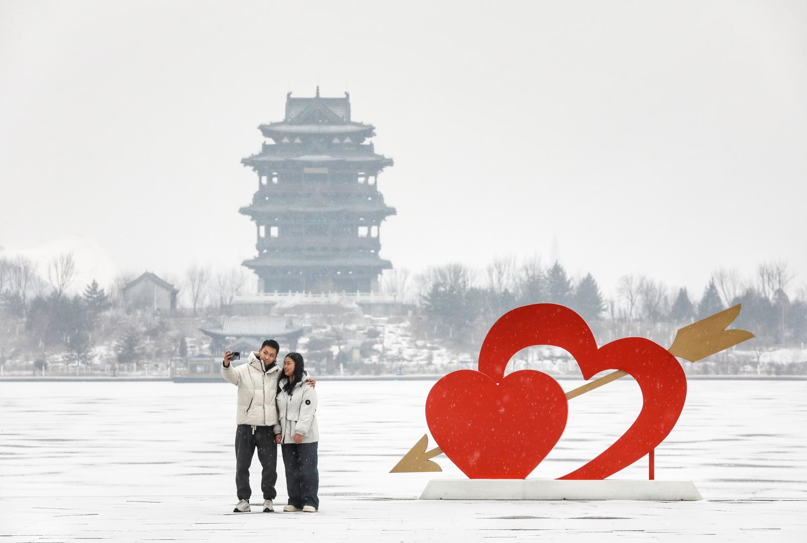 1月25日,吕梁市如意湖畔,一对恋人在雪中留念。