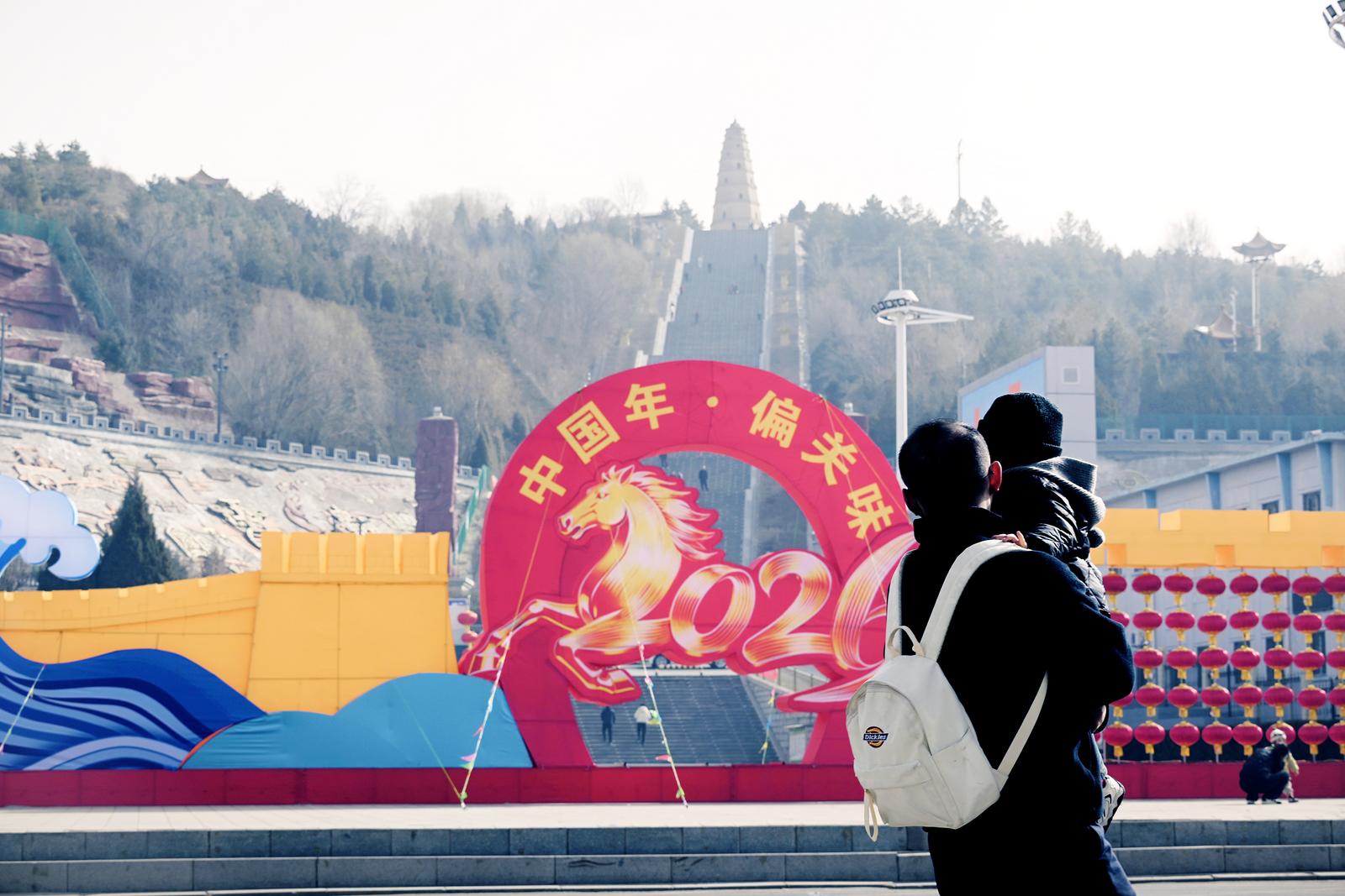 2月20日,市民从忻州市偏关县文笔大街政府广场前的马年造型前走过。 马浩 摄