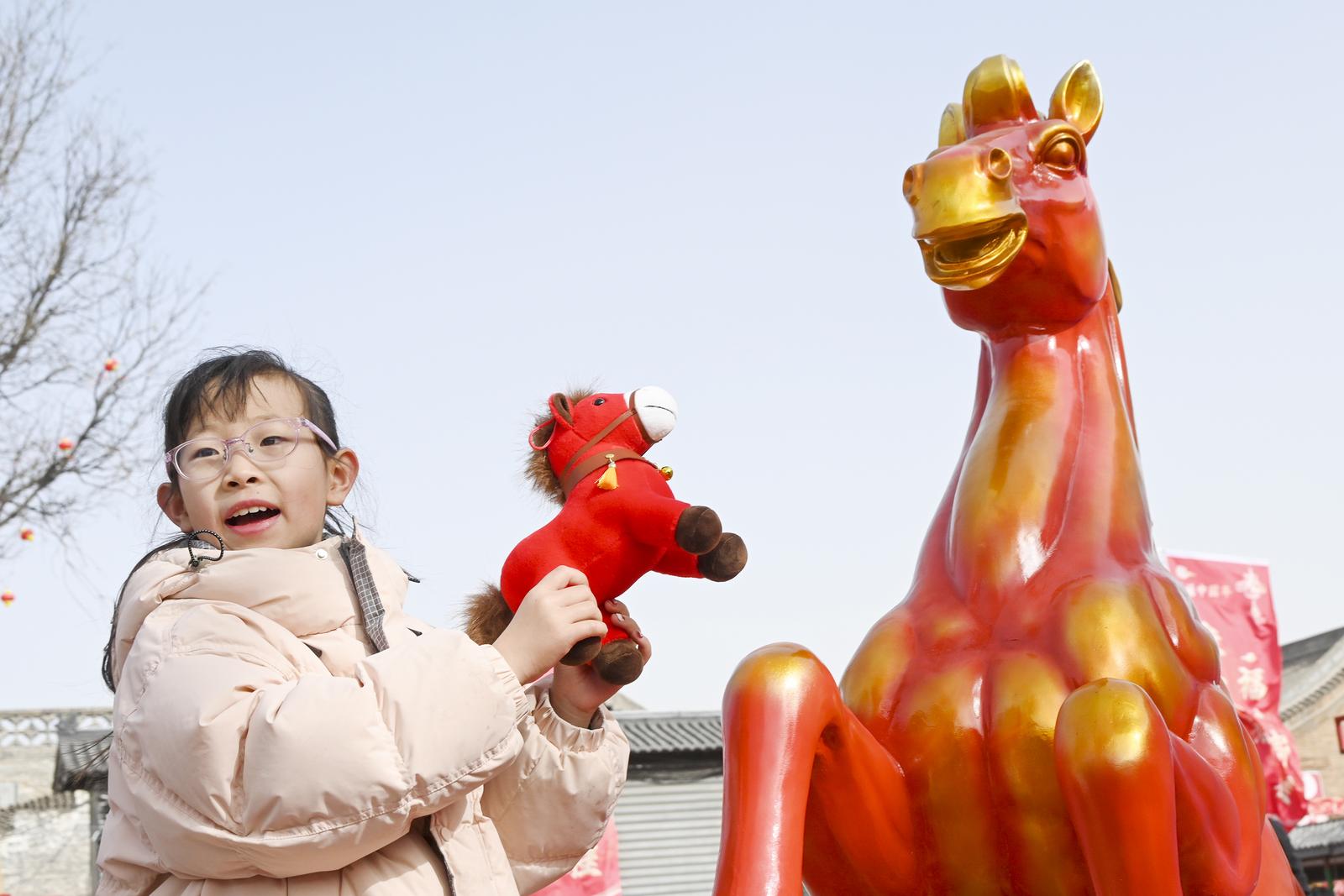 2月21日,游客在平遥古城兴国寺旧址新春文化体验空间与“马”合影。梁生仁 摄
