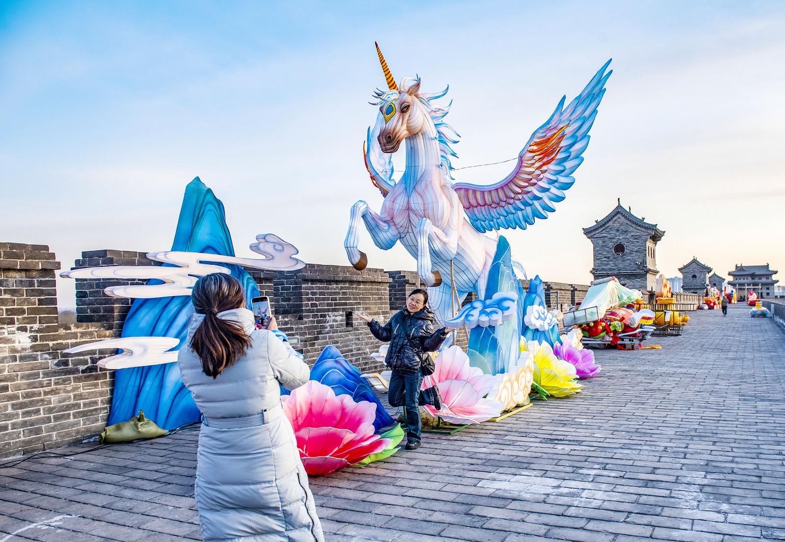春节期间,游客在太原古县城马造型彩灯前合影留念。 蒋云琪 摄