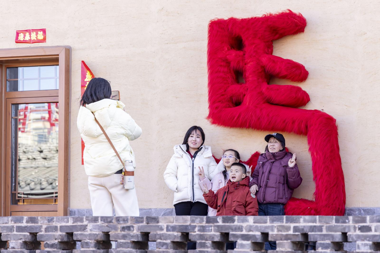 2月18日,在吕梁孝义市高阳镇临水古村,游客在“马”字旁打卡留念。 孙燕 摄 摄