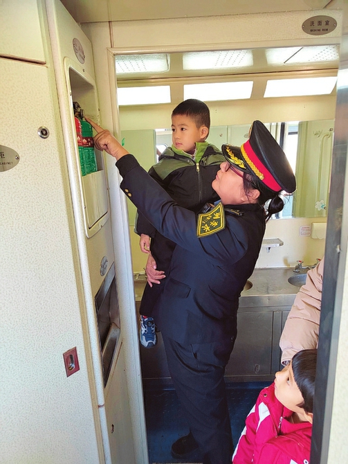 8818/7次列车的列车长正在给小朋友讲述灭火器的使用方式。