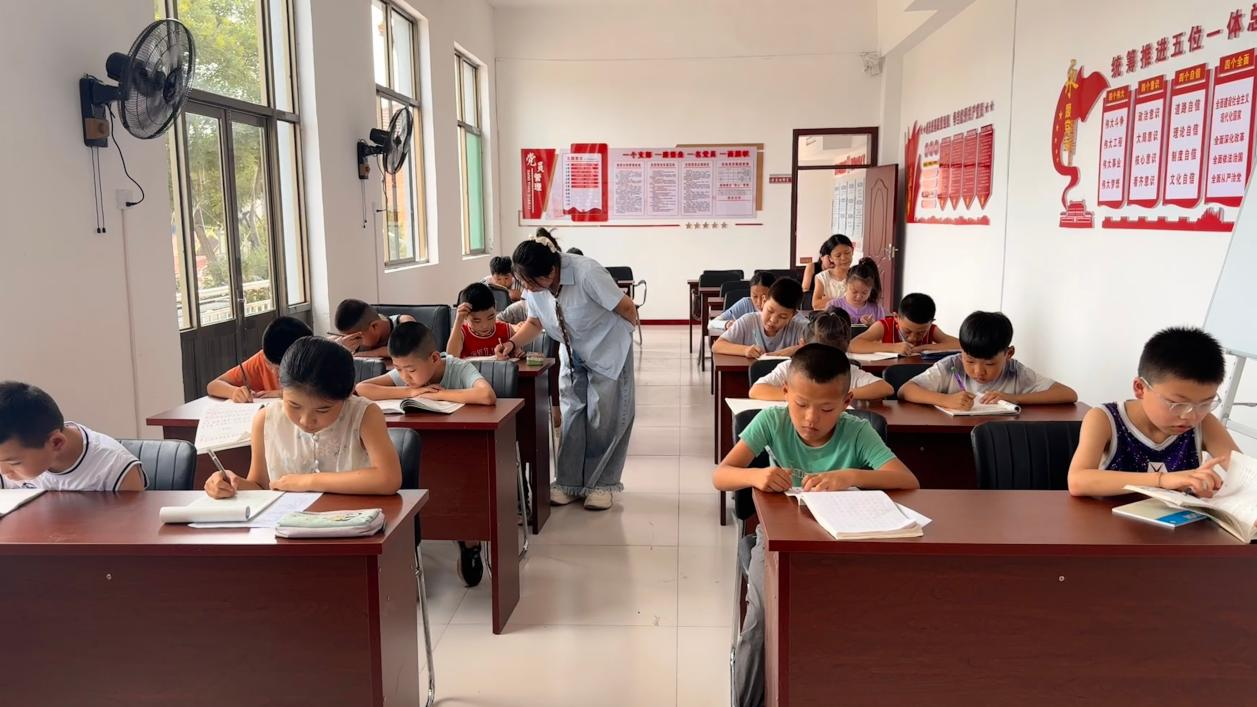 实习实训大学生在翟店街道东天贡村党群服务中心辅导孩子们暑假作业
